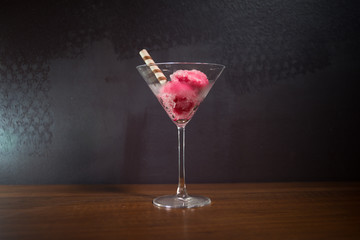 Martini glass filled with colorful fruit ice cream on dark background with toned light and fog