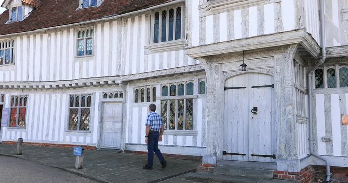 Lavenham England man at Guild House historic village. Lavenham village, civil parish in Suffolk, England. 15th century church, half timbered crooked unlevel medieval cottages and business.
