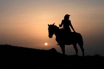 Obraz na płótnie Canvas Silhouette of a horsewoman on a horse at sunset