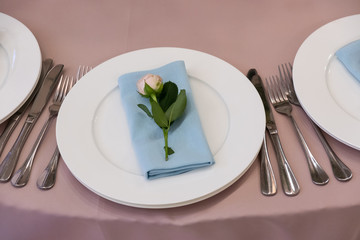 Table with a pink tablecloth, served and decorated with roses