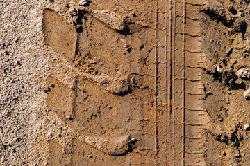 Wheel tracks on the soil. Tire tracks on the ground. Soil texture background. Ground. Soil closeup and high detail. Ground surface. Abstract transportation background texture