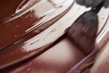 Worker mixing melted chocolate on a factory table 