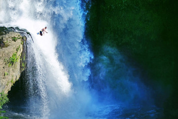 Obraz premium Jumping from the rock into the water. Man having fun at waterfalls in the nature. Bali, Indonesia