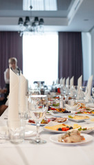 The served festive table is covered with a white tablecloth with dishes and drinks with glasses in the ceremonial hall