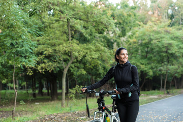 Obraz premium Beautiful woman walking on bicycle in the park outdoors.