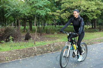 Beautiful woman walking on bicycle in the park outdoors.