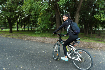 Naklejka premium Beautiful woman walking on bicycle in the park outdoors.