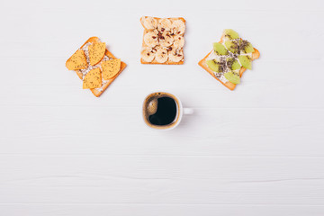 Cup of coffee and three different fruit toast, top view