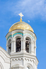 Fototapeta na wymiar bell tower of St. Nicholas Cathedral in Kronstadt, Golden domes in the blue sky 