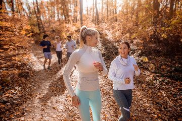 Small group of people running in woods.