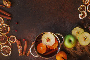 Homemade mulled wine with orange, apple and spices in alluminium casserole on light concrete...