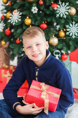 Closeup portrait of happy smiling young kid in home festively decorated Christmas interior. Vertical color photography.