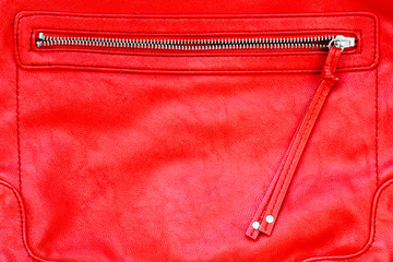 Red leather bag purse and open zipper binding together two layers of red fabric textile under...