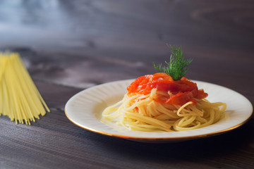 Pasta in tomato sauce in a plate on a wooden table