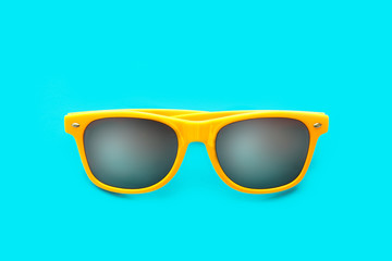 Yellow sunglasses in intense cyan blue background. Minimal image concept for ready for summer, sun...