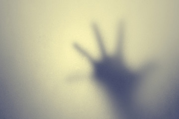 shadow of hand behind frosted glass