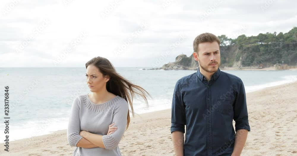 Wall mural angry couple or friends walking after argument ignoring each other on the beach - Wall murals