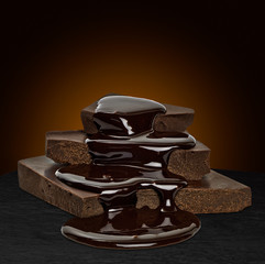 Chocolate sauce flow over cracked chocolate blocks on brown background