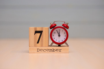 December 7th set on wooden calendar and red alarm clock with blue background.