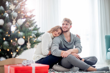 Obraz premium Happy couple in love celebrating Christmas together at home next to Xmas tree