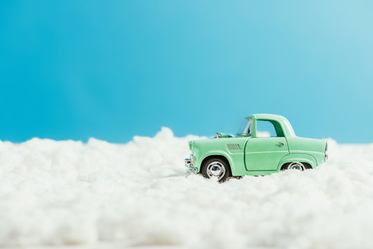 side view of toy car riding by snow made of cotton on blue background - Powered by Adobe