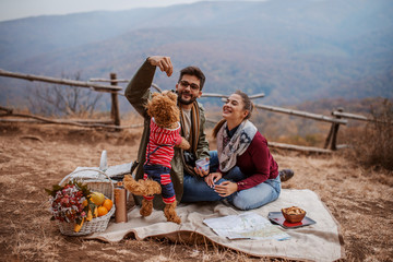 Couple sitting at picnic and playing with dog.