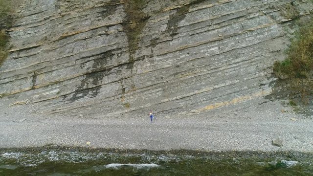 Woman is doing yoga and physical exercises for legs on rock background. Aerial beautiful footage view.