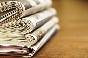 Pile of fresh morning newspapers on the table at office. Latest financial and business news in daily paper. Pages with information (headlines, articles, photos, text). Folded and stacked journals  