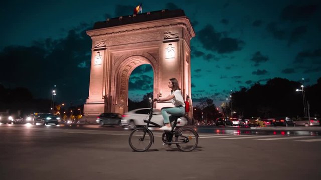 Woman cycling at arcul de triumf in bucharest at night