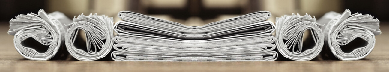 Long horizontal banner with rolled and folded newspapers and magazines in retro style. Concept for news and information - could be used for web design or advertisement