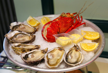 Large dish with fresh seafood, oysters with lobster with lemon and sauce on ice