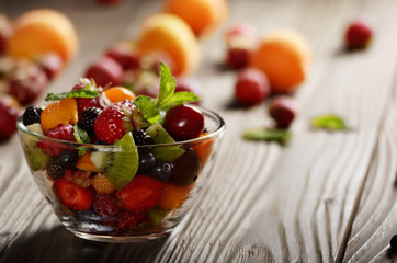 Assorted fruits in glass bowl on kitchen wooden table