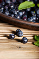 Clay plate full of Ripe organic blueberries on wooden table