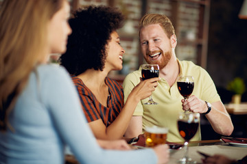Friends making a toast while sitting in restaurant. Multi-ethnic group.