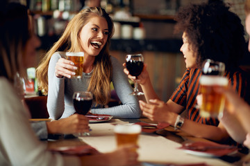 Multicultural friends sitting in restaurant and drinking wine and beer. - 233181879