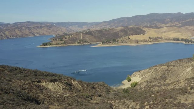 A blue lake in between hills with power boats and kayaks