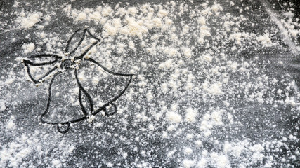 Christmas bells with bow made from flour on black wooden background