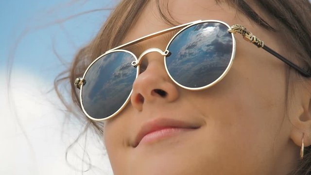 A child in sunglasses. Reflection of the sky in sunglasses.