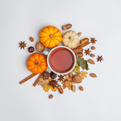 Autumn composition. A cup of fragrant tea surrounded by dry leaves, nuts and pumpkins