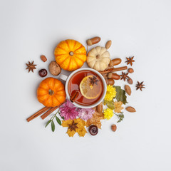 Autumn composition. A cup of fragrant tea surrounded by dry leaves, nuts, flovers and pumpkins