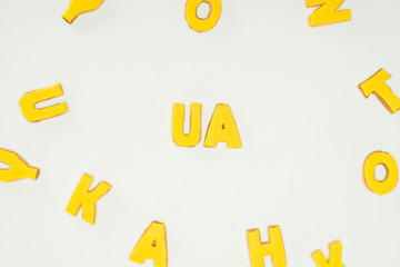 ua sign made of yellow cookies and scattered alphabet letters isolated on white background