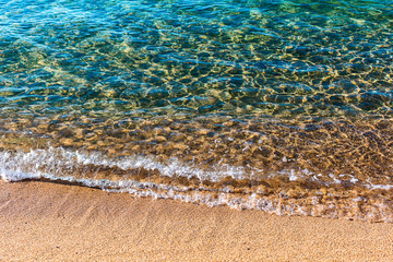 Sandy beach of warm sea. Transparent turquoise water, soft wave, sunlight reflecting on sea bottom
