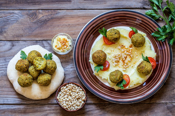 falafel with pita, hummus and pine nuts on wooden background