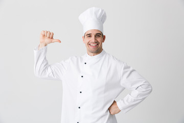 Excited young man chef indoors isolated over white wall background pointing.