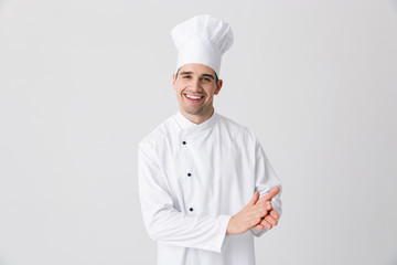 Handsome young man chef indoors isolated over white wall background posing.