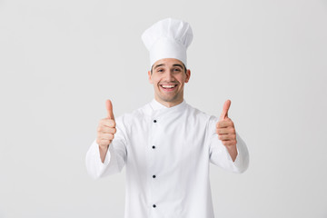 Excited young man chef indoors isolated over white wall background showing thumbs up gesture.