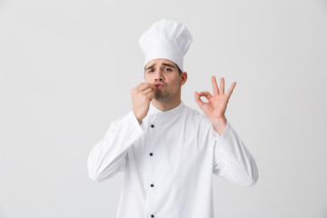 Handsome young man chef indoors isolated over white wall background.