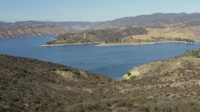 A blue lake in between hills with power boats and kayaks