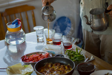 Hands of senior man with metal Turkish teapot pouring tea into glass cups for breakfast. Old Turkish man pouring tea.