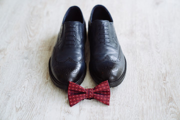 Men's leather shoes, bow tie and boutonniere on a white table background. Clothing accessories businessman.